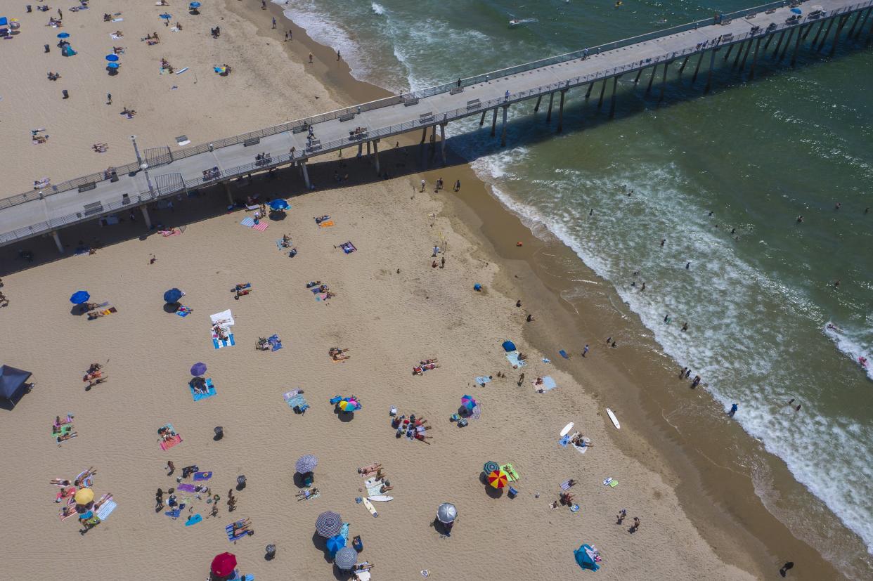 An aerial view shows people on the beach and in the water during a heatwave as coronavirus cases reach new record levels in states across the nation in Hermosa Beach, Calif. on July 12, 2020. Los Angeles County beaches are reopened after they were re-closed over the Fourth of July weekend because of fears that large gatherings would further accelerate the spread of COVIC-19. More than 2,000 people are currently hospitalized with COVID-19 in Los Angeles County.