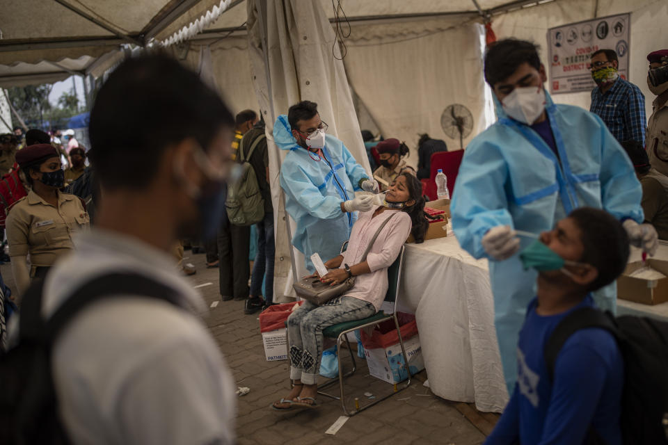 Health workers take nasal swab samples of passengers to test for COVID-19 at a bus terminal in New Delhi, India, Wednesday, March 24, 2021. (AP Photo/Altaf Qadri)