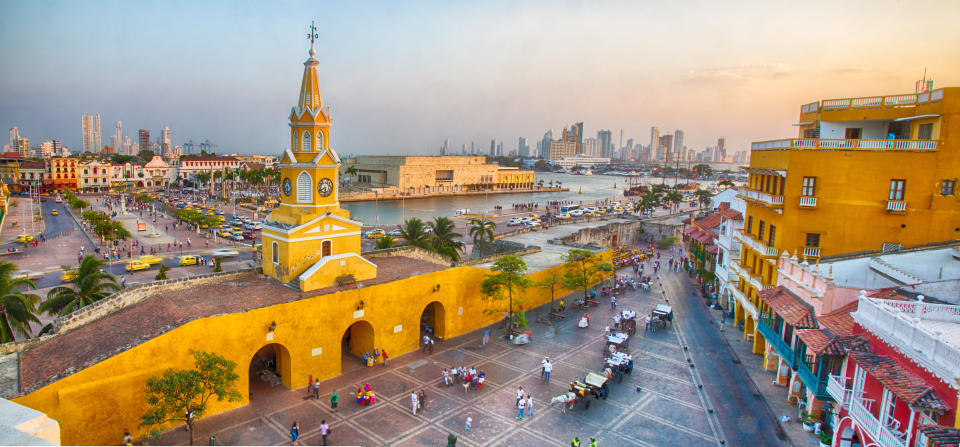 Cartagena, Colombia - February 21st, 2014: Horsedrawn carriages and haukers wait for tourists and restaurant goers in the Plaza San Pedro Claver. The Towers of Bocagrande in the background.