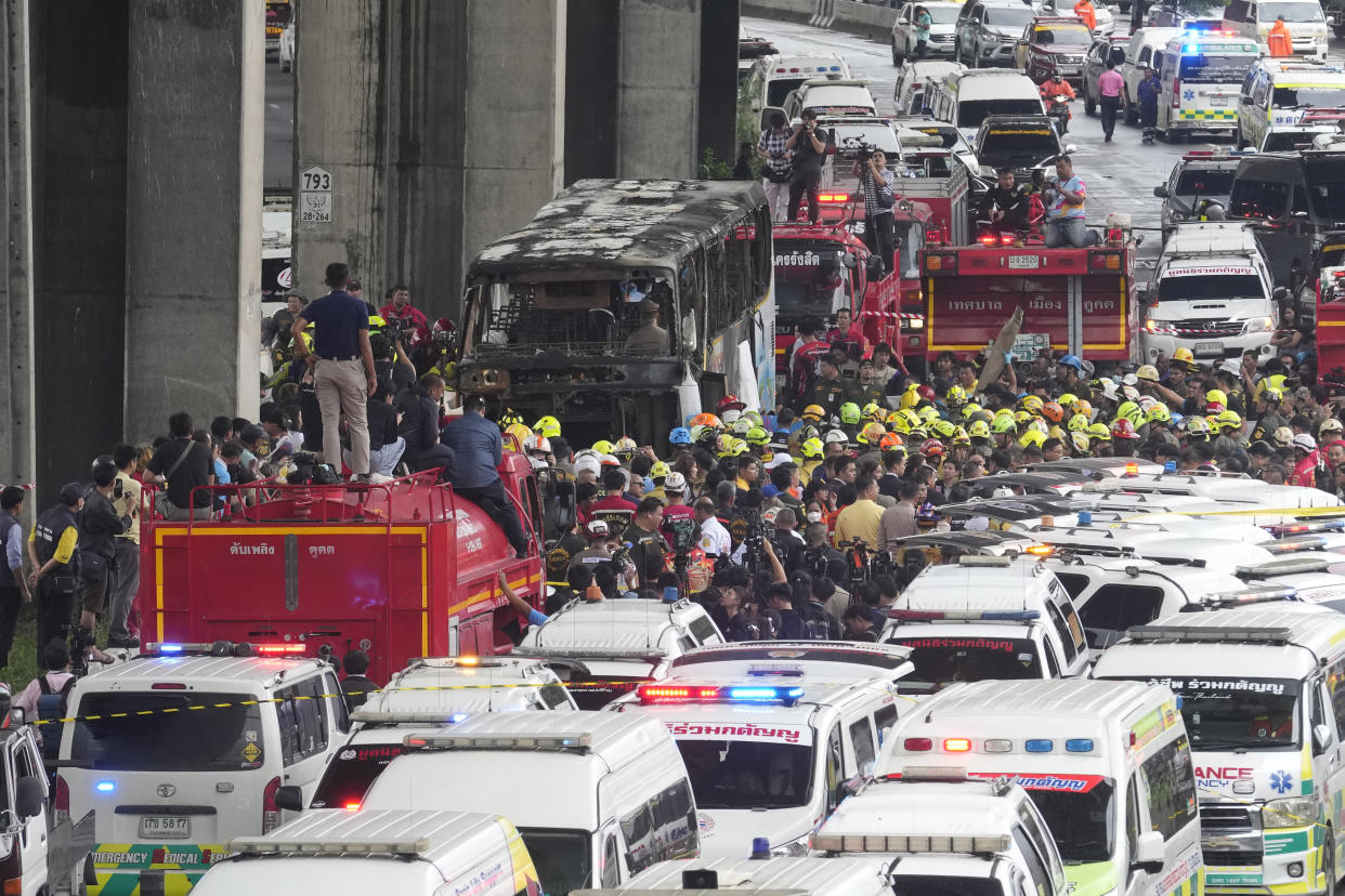 Rescuers gather at the site of a bus that caught fire, carrying young students with their teachers, in suburban Bangkok, Tuesday, Oct. 1, 2024. (AP Photo/Sakchai Lalit)