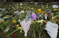 A photo of Britain's Prince Philip is among flowers left by the public outside the gates of Windsor Castle, a day after the death of Britain's Prince Philip, in Windsor, England, Saturday, April 10, 2021. Britain's Prince Philip, the irascible and tough-minded husband of Queen Elizabeth II who spent more than seven decades supporting his wife in a role that mostly defined his life, died on Friday. (AP Photo/Frank Augstein)