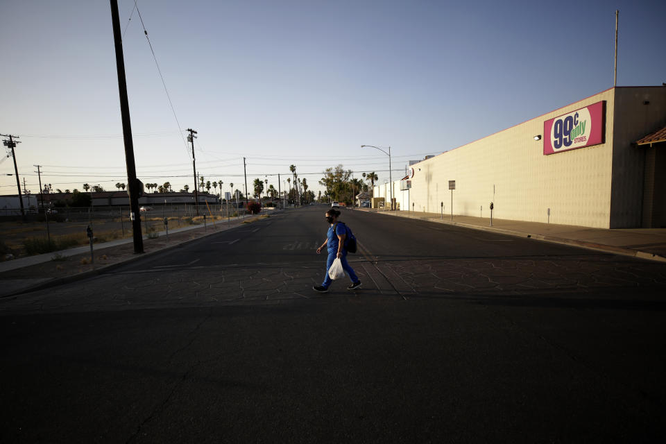 Dulce Garcia carries groceries as she makes her way home to Mexico after work Wednesday, July 22, 2020, in Calexico, Calif. (AP Photo/Gregory Bull)