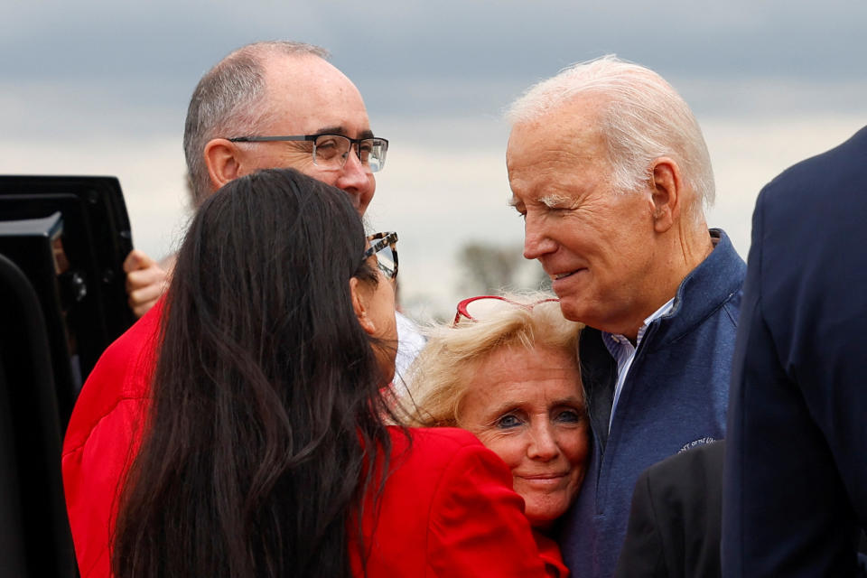 President Biden is greeted by Rep. Debbie Dingell, center, Shawn Fain, top left, president of the United Auto Workers, and Rep. Rashida Tlaib, lower left