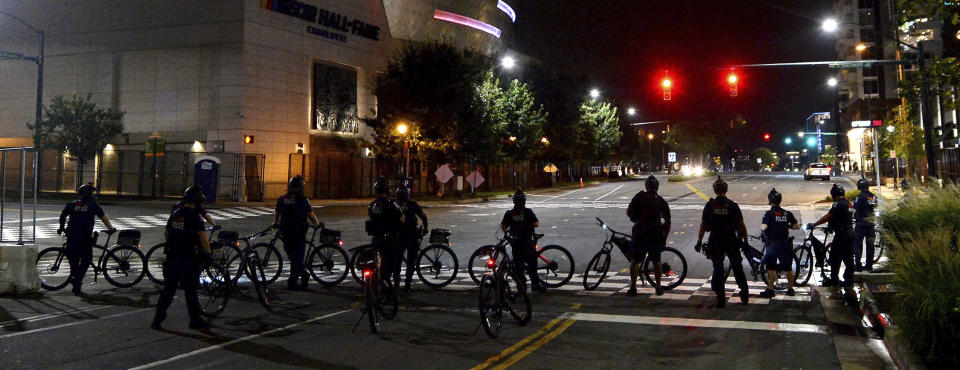 Charlotte Mecklenburg Police bike officers wait at the intersection of Brevard Street and Stonewall Street as demonstrators protest, in uptown Charlotte, N.C., Friday, Aug. 21, 2020. (Jeff Siner/The Charlotte Observer via AP)