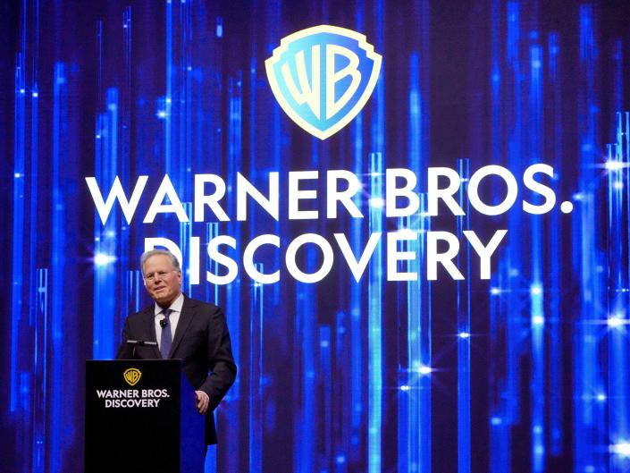 David Zaslav speaks in front of Warner Bros.  Discovery logo on the blue curtain