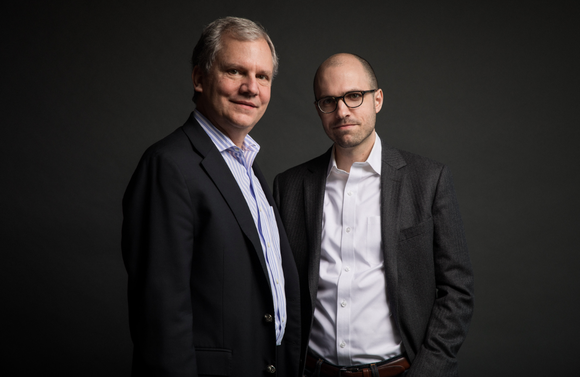 Arthur Sulzberger, Jr. and A.G. Sulzberger of The New York Times pose in front of a black backdrop in a professional photo