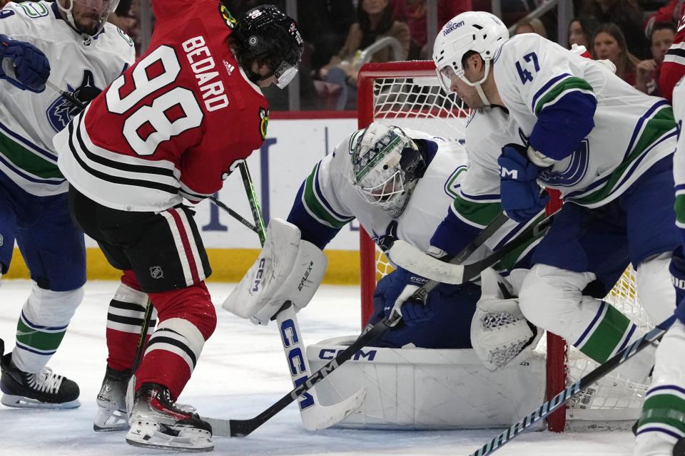 Vancouver Canucks goaltender Thatcher Demko, right, saves a shot by Chicago Blackhawks center Connor Bedard (98) during the second period of an NHL hockey game in Chicago, Sunday, Dec. 17, 2023. (AP Photo/Nam Y. Huh)