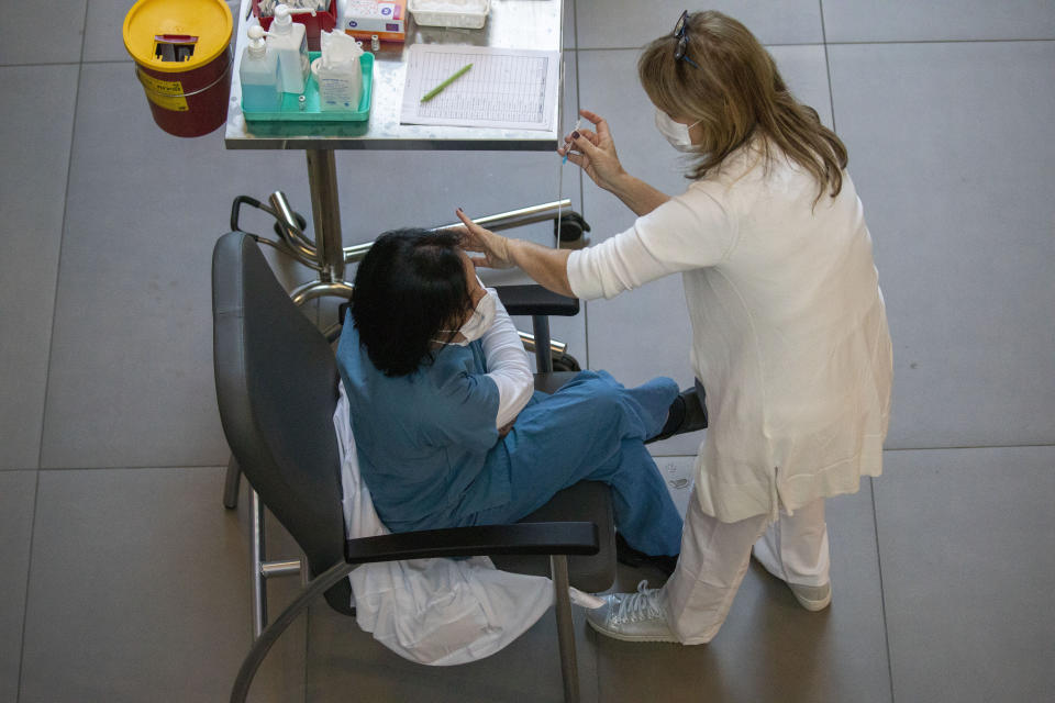 A medical staff member receives a COVID-19 coronavirus vaccine at the Ichilov Hospital in Tel Aviv, Israel, Sunday, Dec. 20, 2020. (AP Photo/Ariel Schalit)