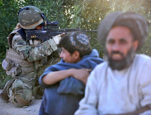 Afghan residents look on as a soldier from 1st Battalion the Royal Gurkha Rifles patrols in a village in Nahr e Saraj, Helmand on Saturday. Prime Minister David Cameron said he was "deeply saddened" by the killing of three British soldiers in Nahr-e-Saraj