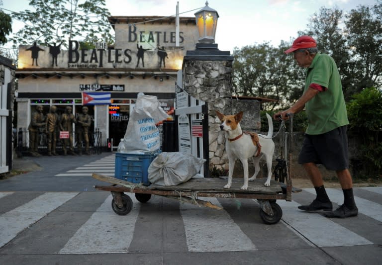 A man with his dog walks next to The Beatles bar in Varadero, Matanza, on March 17, 2017