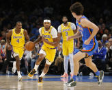 Los Angeles Lakers forward Kent Bazemore (9) drives the ball against Oklahoma City Thunder guard Josh Giddey (3) while Los Angeles Lakers guard Rajon Rondo (4) and forward Anthony Davis (3) look on during the first half of an NBA basketball game, Wednesday, Oct. 27, 2021, in Oklahoma City. (AP Photo/Garett Fisbeck)