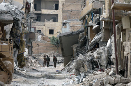 Fighters from Syrian Democratic Forces (SDF) walk together along a damaged street in Raqqa, Syria September 16, 2017. REUTERS/ Rodi Said