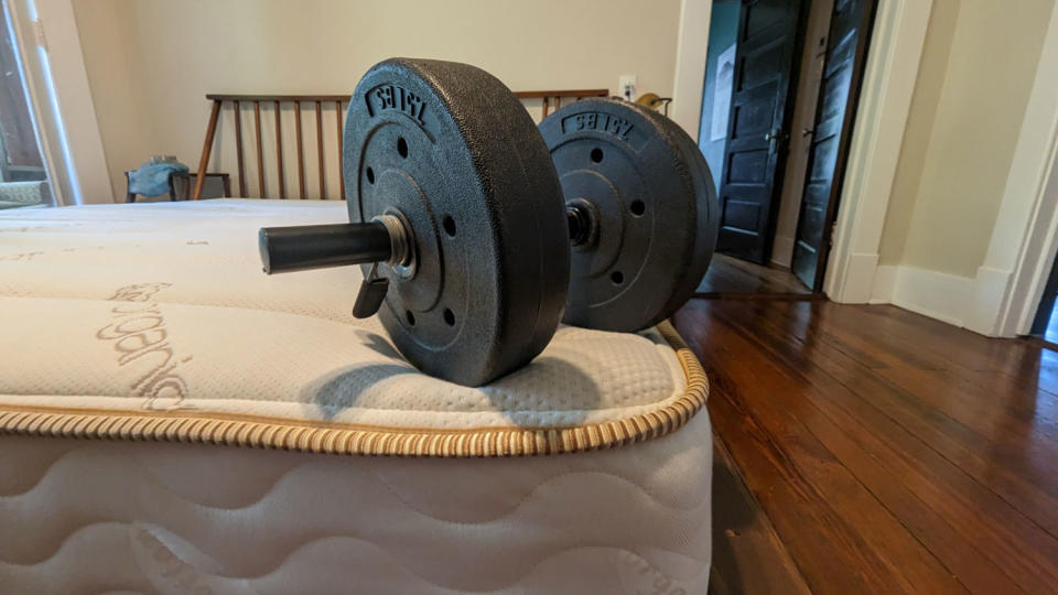 A dumbbell on the edge of the Saatva Memory Foam Hybrid mattress