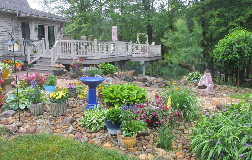 The garden of Bill and Lisa Pim, at 10936 Township Road 262, features flower beds around the house and throughout the yard containing unique pieces of wood and rock.