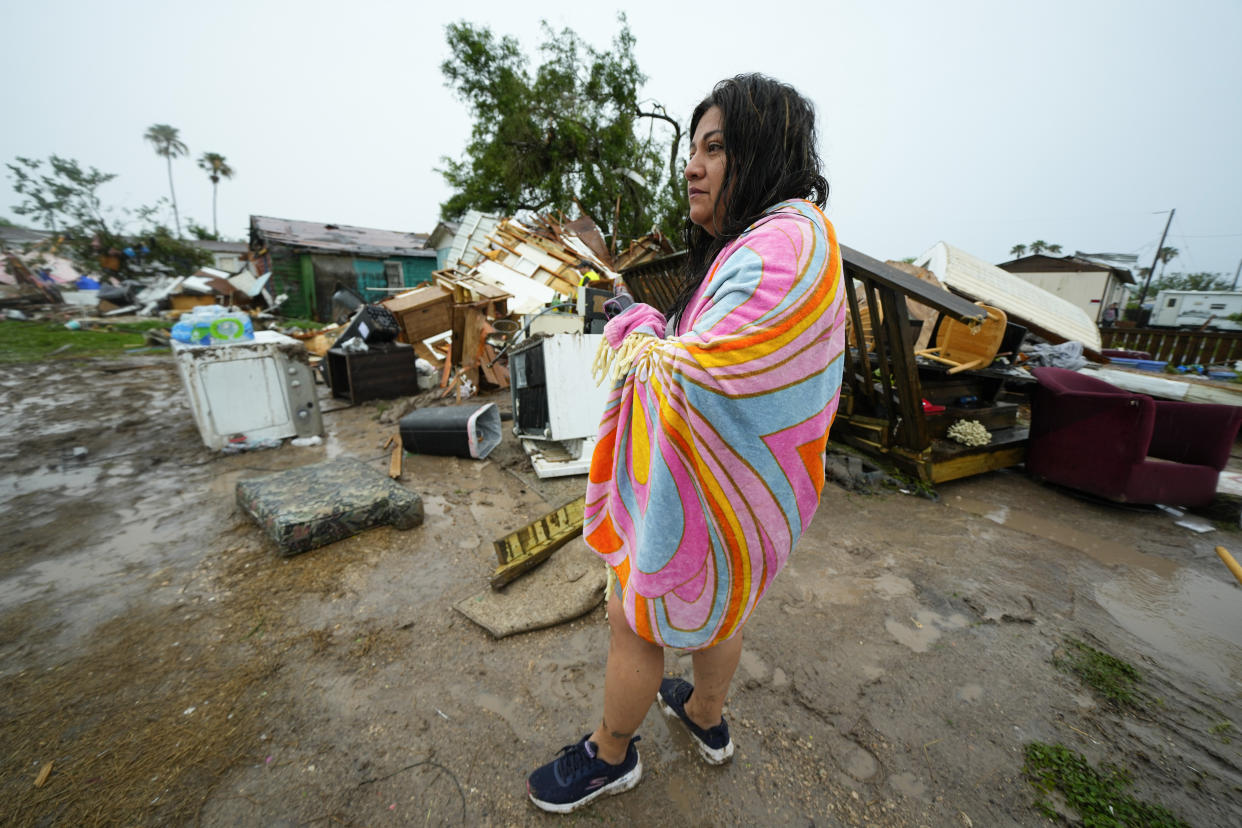 A woman stands outside of her home after a tornado hit Saturday, May 13, 2023, in the unincorporated community of Laguna Heights, Texas near South Padre Island. Authorities say one person was killed when a tornado struck the southernmost tip of Texas on the Gulf coast. (AP Photo/Julio Cortez)