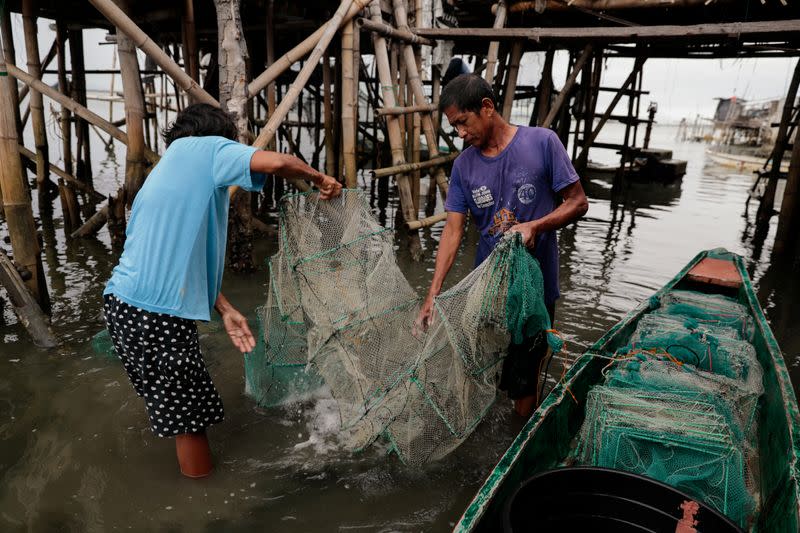 The Wider Image: Rising seas threaten early end for sinking village in Philippines