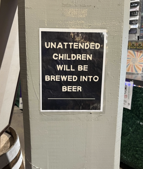 Sign humorously reads: "UNATTENDED CHILDREN WILL BE BREWED INTO BEER." Affixed to a light gray column