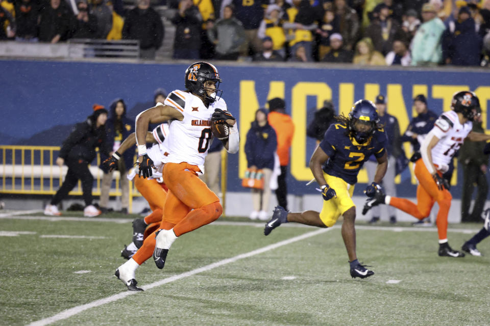 Oklahoma State's Ollie Gordon, left, carries the ball for a big rushing touchdown against West Virginia during the second half of an NCAA college football game Saturday, Oct. 21, 2023, in Morgantown, W.Va. (AP Photo/Chris Jackson)