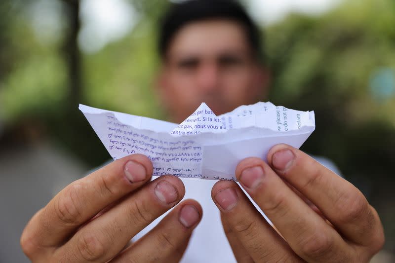 Mohamed, a young Kurdish migrant, poses with an origami boat that he built in a makeshift camp in Grande-Synthe