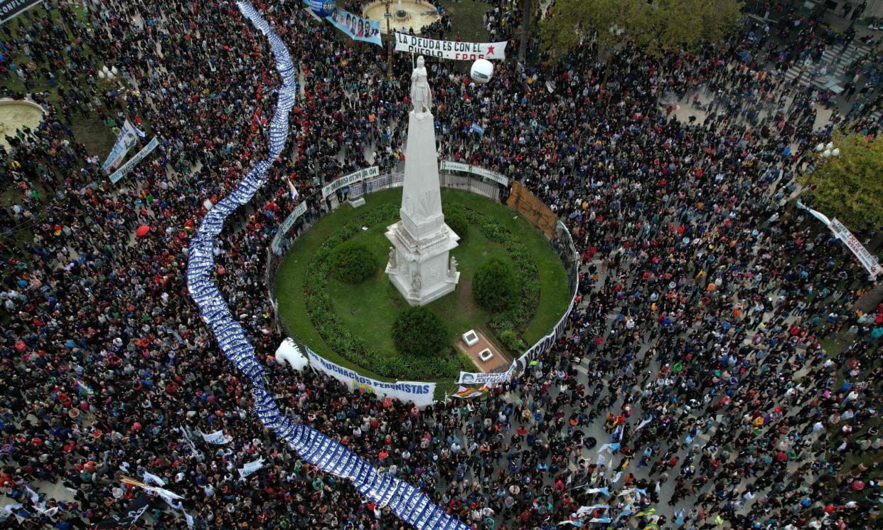 <span>Hundreds of people carry a large banner with portraits of people disappeared during the military dictatorship (1976-1983) at Plaza de Mayo Square in Buenos Aires on 24 March 2022.</span><span>Photograph: Elena Boffetta/AFP/Getty Images</span>