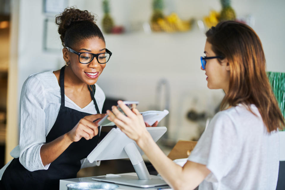 Woman showing cashier a coupon on her phone