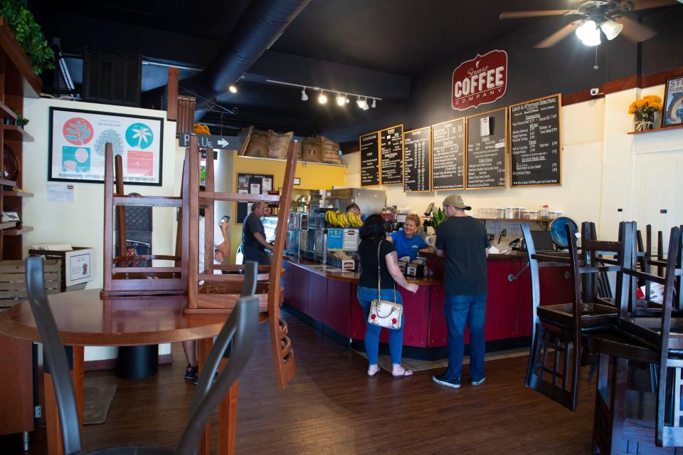 Stuart Coffee Co. co-owner Roslyn Boop (center) serves Brittany Nahrstedt (left) and Brenden Yarbrough (right), both of Port St. Lucie, on Monday, March 23, 2020, in downtown Stuart. The couple had cabin fever and wanted to get outside, Yarbrough said. Although March is the highest revenue month for many businesses in downtown Stuart, many stores have closed their doors and restaurants, by mandate from Gov. Ron DeSantis, are only serving carry out food and alcohol orders to prevent the spread of coronavirus.