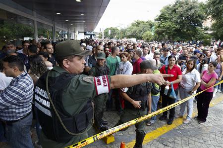 Venezuelan soldiers control the crowd as people wait to shop for electronic goods outside a Daka store in Caracas November 9, 2013. REUTERS/Carlos Garcia Rawlins