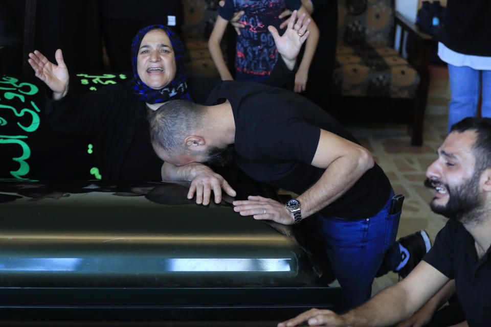 Relatives of the victims weep over the coffins in the town of Ainata, a Lebanese border village with Israel in south Lebanon, Tuesday, Nov. 7, 2023. A Lebanese woman and her three grand daughters were laid to rest in their hometown in southern Lebanon two days after they were killed in an Israeli drone strike while in a car near the Lebanon-Israel border. (AP Photo/Mohammed Zaatari)