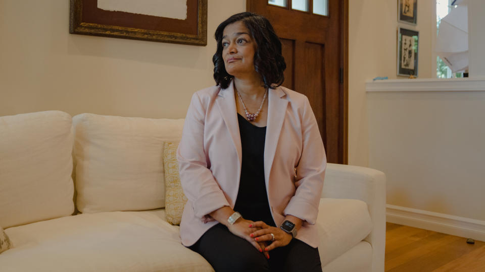 Rep. Pramila Jayapal, seated on a couch in her living room.