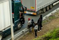 Migrants speak with a truck driver as they walk alongside vehicles on the route leading to the Channel Tunnel in Coquelles near Calais, northern France on July 29, 2015