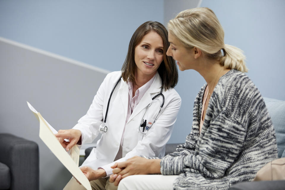 Doctor in a white coat discussing a document with a female patient in a waiting room