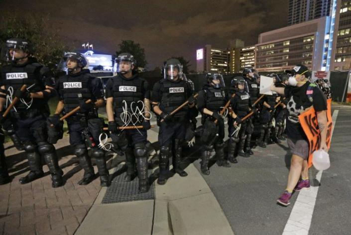 A protester walks in front of a line of police officers on Thursday, the third night of protests in Charlotte, N.C. (Photo: Chuck Burton/AP)