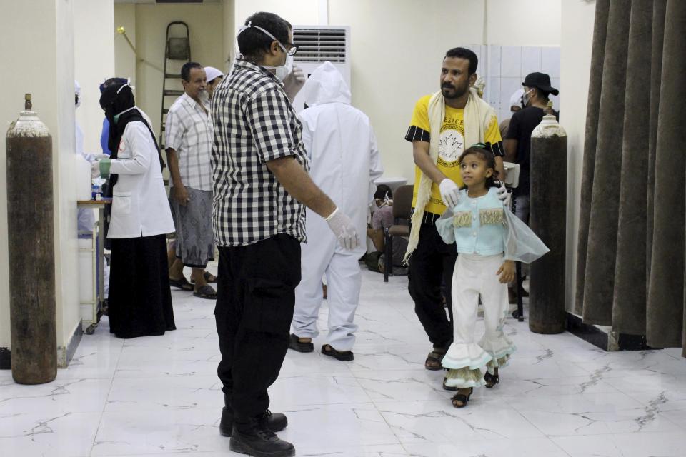 In this May 12, 2020 photo, Yemeni medical workers wearing masks and protective gear talk to patients at hospital in Aden, Yemen. People have been dying by the dozens each day in southern Yemen's main city, Aden, many of them with breathing difficulties, say city officials. Blinded with little capacity to test, health workers fear the coronavirus is running out of control, feeding off a civil war that has completely broken down the country. (AP Photo/Wail al-Qubaty)