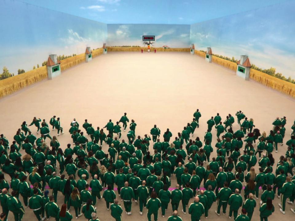 A crowd in green running across a room in "Squid Game: The Challenge"