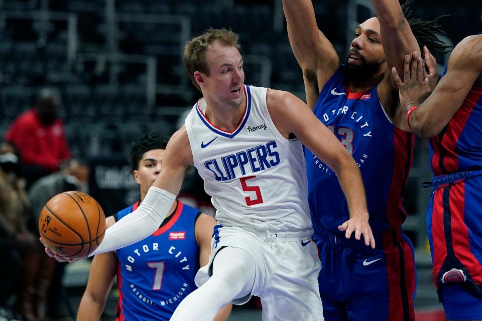 LA Clippers guard Luke Kennard (5) passes as Detroit Pistons center Jahlil Okafor (13) defends under the basket during the first half of an NBA basketball game, Wednesday, April 14, 2021, in Detroit. (AP Photo/Carlos Osorio)