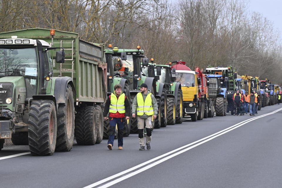 Czech farmers walk by tractors at the Hodonín/Holíč, Czech-Slovakia border crossing, in Czech Republic, Thursday, Feb. 22, 2024. Czech farmers were driving their tractors and other vehicles to the country’s borders on Thursday to meet their colleagues from neighboring countries and join forces in their protests against European Union agriculture policies, bureaucracy and overall conditions for their business. (Vaclav Salek/CTK via AP) /CTK via AP)