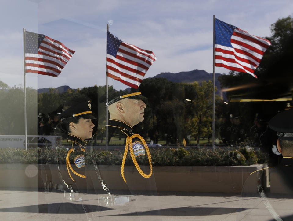 American flags are reflected on a window as law enforcement personnel await the arrival of a procession carrying the body of Ventura County Sheriff's Sgt. Ron Helus at the Calvary Community Church Thursday, Nov. 15, 2018, in Westlake Village, Calif. Helus was fatally shot while responding to a mass shooting at a country music bar in Southern California. (AP Photo/Marcio Jose Sanchez, Pool)