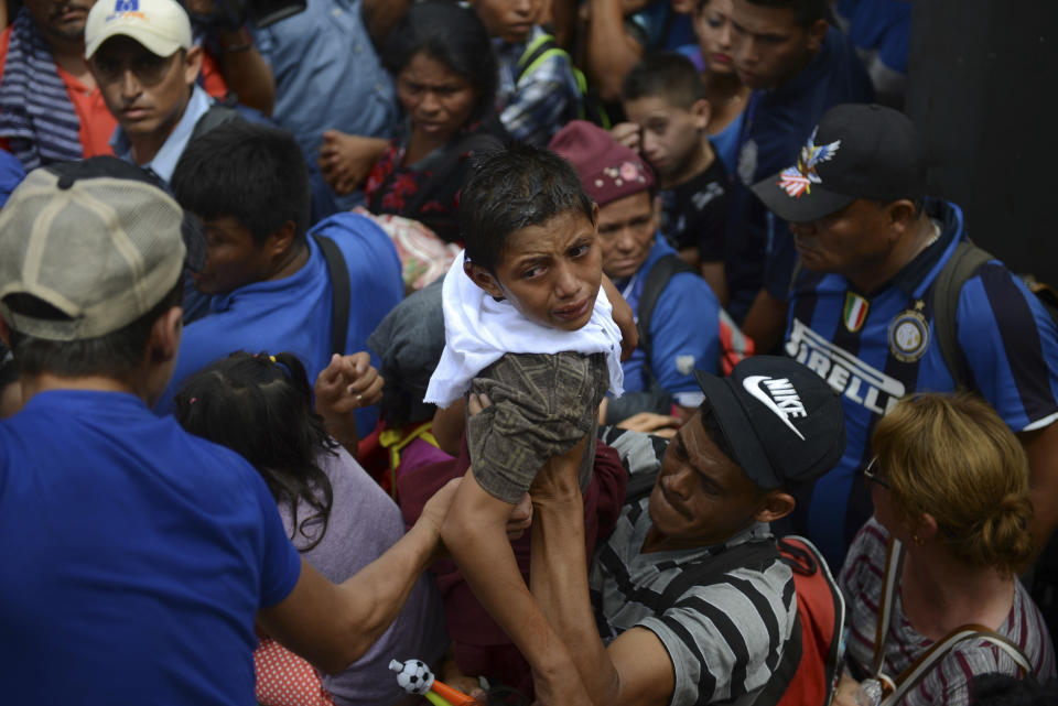 A boy cries as he is brought back down after an unsuccessful attempt to lift him over a border fence, in Tecun Uman, Guatemala, Friday, Oct. 19, 2018. Earlier in the day, waving Honduran flags and carrying umbrellas to protect against the sun, thousands of migrants arrived at the Guatemalan side of the border with Mexico, demanding they be allowed passage. (AP Photo/Oliver de Ros)