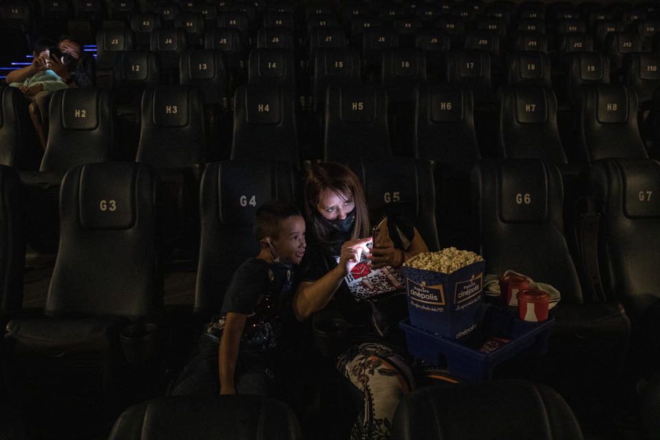 Vivenka Ivanovich and her 6-year-old son Mateo Blanco, wait for the start of a movie at the Cinepolis cinema on the first day after the COVID-19 lockdown in Santiago, Chile, Feb. 18, 2021. The cinemas authorized to open are those located in the communes that are in the intermediate phases of sanitary restrictions. (AP Photo/Esteban Felix)