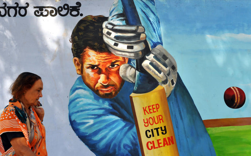 An Indian commuter walks past a painting of Indian cricketer Sachin Tendulkar on the boundary wall of a sports ground in Bangalore. Tendulkar achieved an unbeaten score of 200 runs in the recently concluded Gwalior One Day International (ODI) match against South Africa.<br>AFP PHOTO/Dibyangshu Sarkar