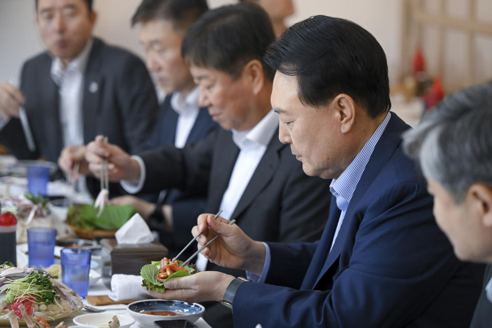 South Korean President Yoon Suk Yeol, second from right, eats seafood for lunch at the Noryangjin fish market in Seoul, South Korea, Thursday, Aug. 31, 2023. Yoon visited the fish market as part of effort to boost consumption of local fisheries amid public concern about Japan's release of radioactive water into the ocean. (South Korea Presidential Office /Yonhap via AP)