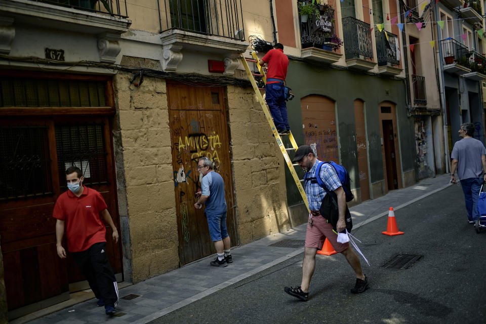 People walk along a street during sunny weather, in Pamplona, northern Spain, Tuesday, June 2, 2020, as measures to control the spread of coronavirus were eased. (AP Photo/Alvaro Barrientos)