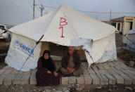 Syrians who are newly displaced by the Turkish military operation in northeastern Syria, sit in front of a tent upon their arrival at the Bardarash camp, north of Mosul, Iraq, Wednesday, Oct. 16, 2019. The camp used to host Iraqis displaced from Mosul during the fight against the Islamic State group and was closed two years ago. The U.N. says more around 160,000 Syrians have been displaced since the Turkish operation started last week, most of them internally in Syria. (AP Photo/Hussein Malla)