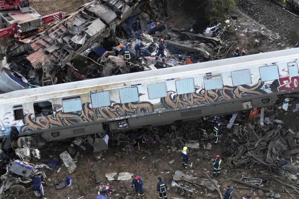 Firefighters and rescuers operate after a collision in Tempe near Larissa city, Greece, Wednesday, March 1, 2023. A train carrying hundreds of passengers has collided with an oncoming freight train in northern Greece, killing and injuring dozens passengers. (AP Photo/Vaggelis Kousioras)