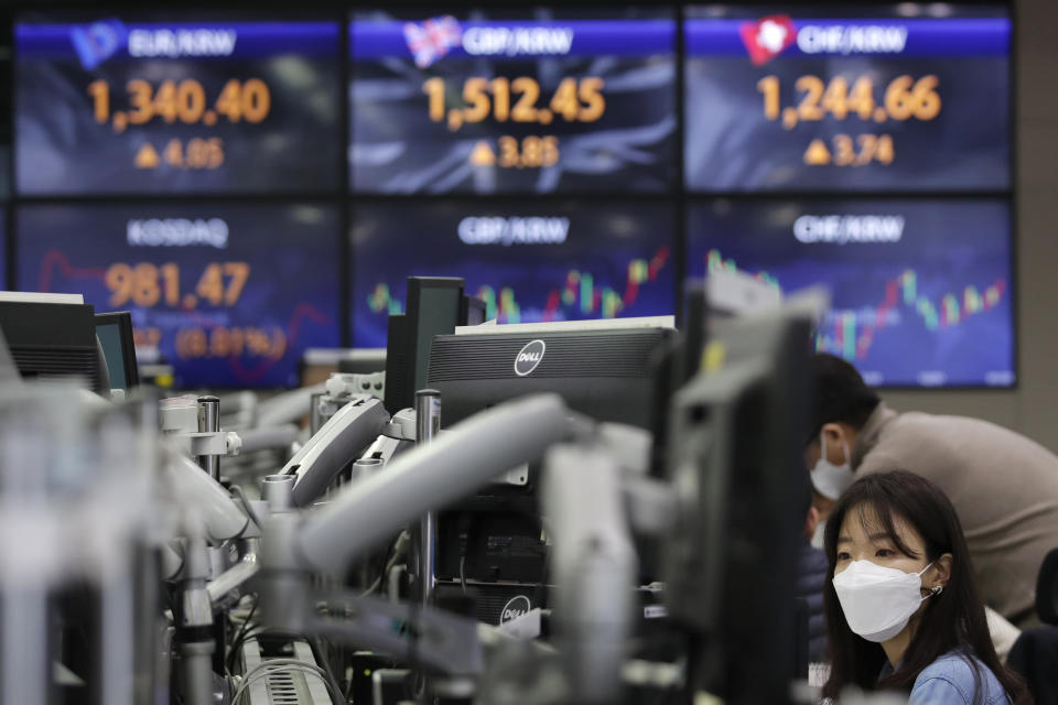 A currency trader watches computer monitors near the screens showing the foreign exchange rates at the foreign exchange dealing room in Seoul, South Korea, Friday, Jan. 22, 2021. Asian stock markets retreated Friday after a resurgence of coronavirus infections in China and a rise in cases in Southeast Asia.(AP Photo/Lee Jin-man)