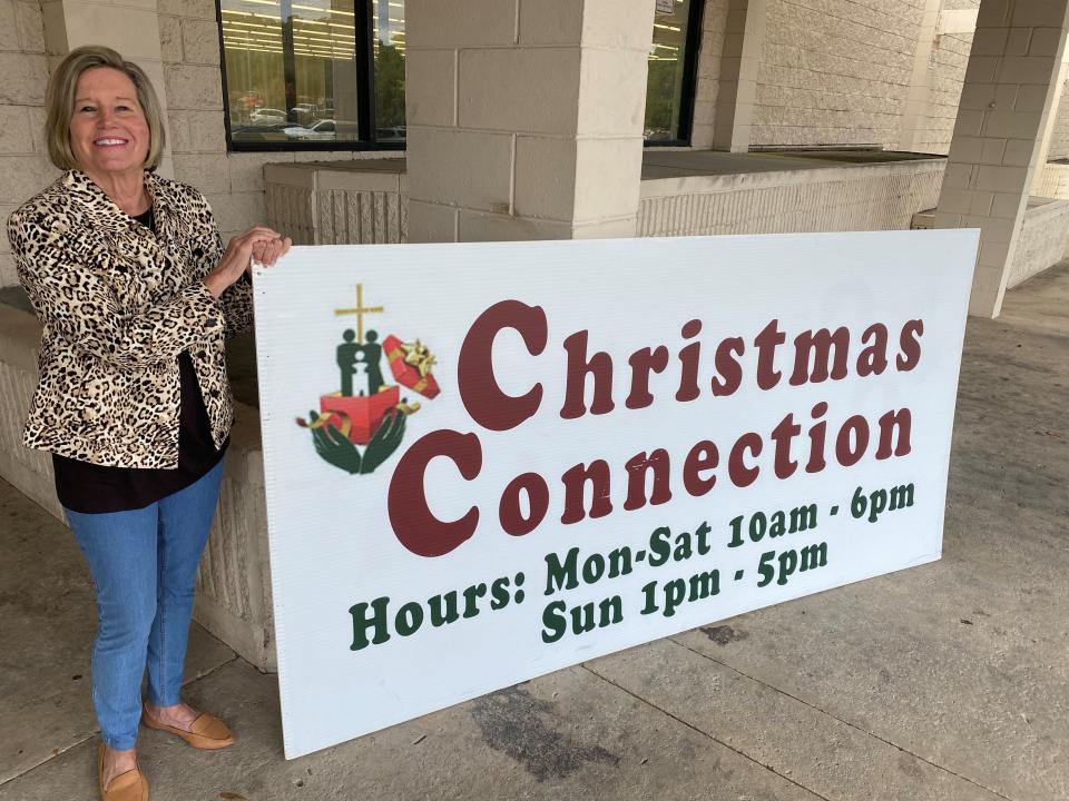 Lisa Harvey poses with a banner outside 2021 Christmas Connection drop-off location at 2990-2 Apalachee Parkway, Tallahassee.