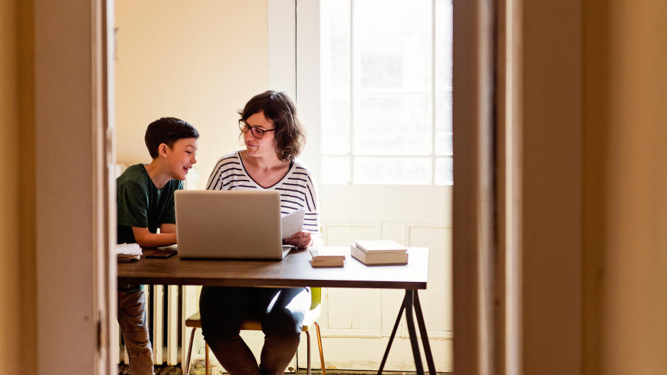 Single mother working from home with son coming in to have his homework reviewed.