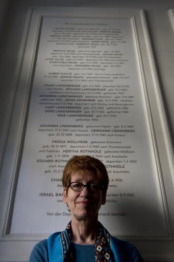 Berlin tenant Gabrielle Pfaff stands last month in front of a plaque commemorating Jews evicted during the Nazi era from the building in which she lives. Thanks to the efforts of a group of Berliners to trace the Jewish residents who once lived in their building, the victims are finally being openly remembered