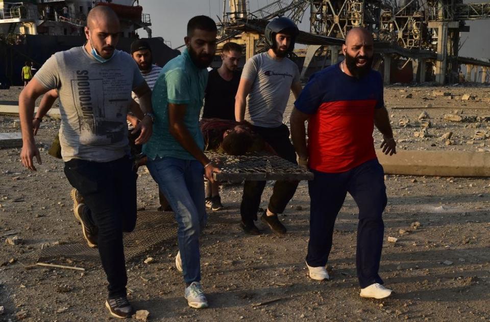 People carry a wounded man after a fire at a warehouse with explosives at the Port of Beirut led to massive blasts in Beirut