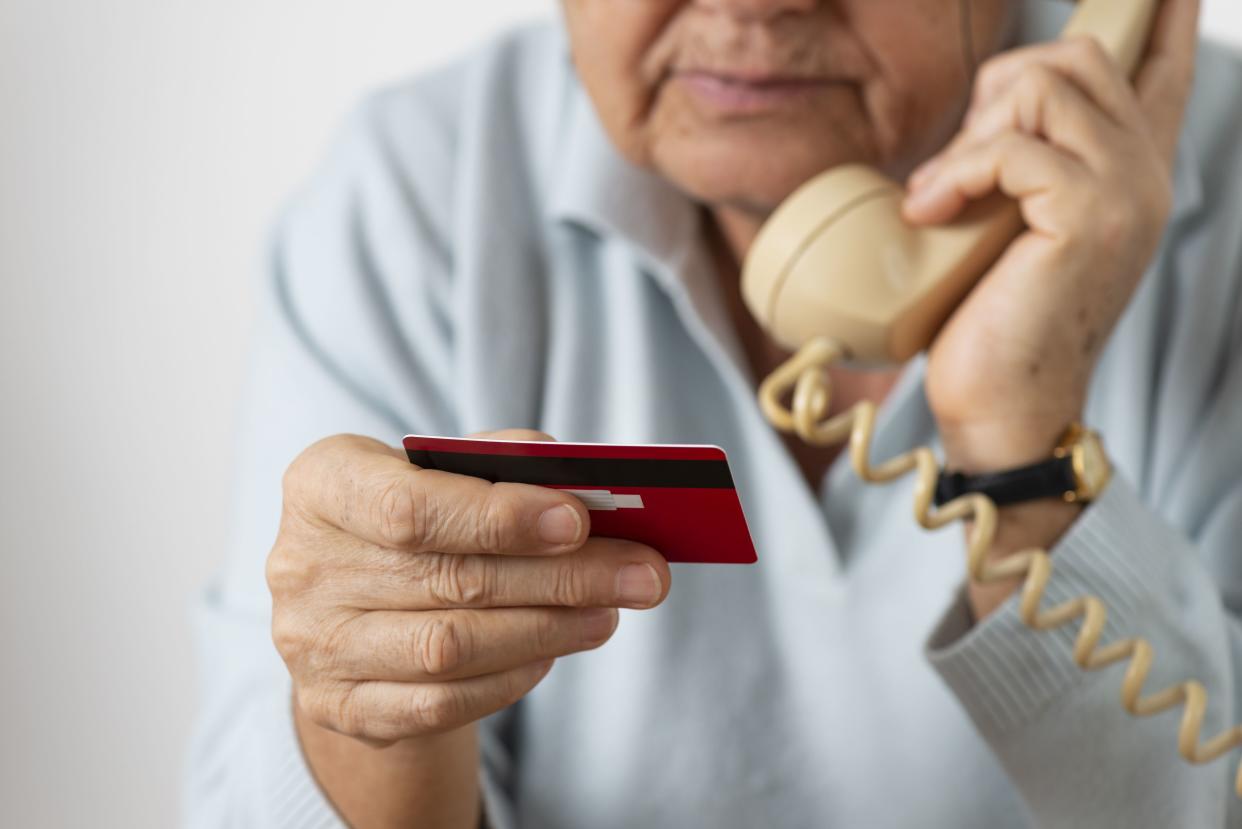 senior on the phone with a credit card